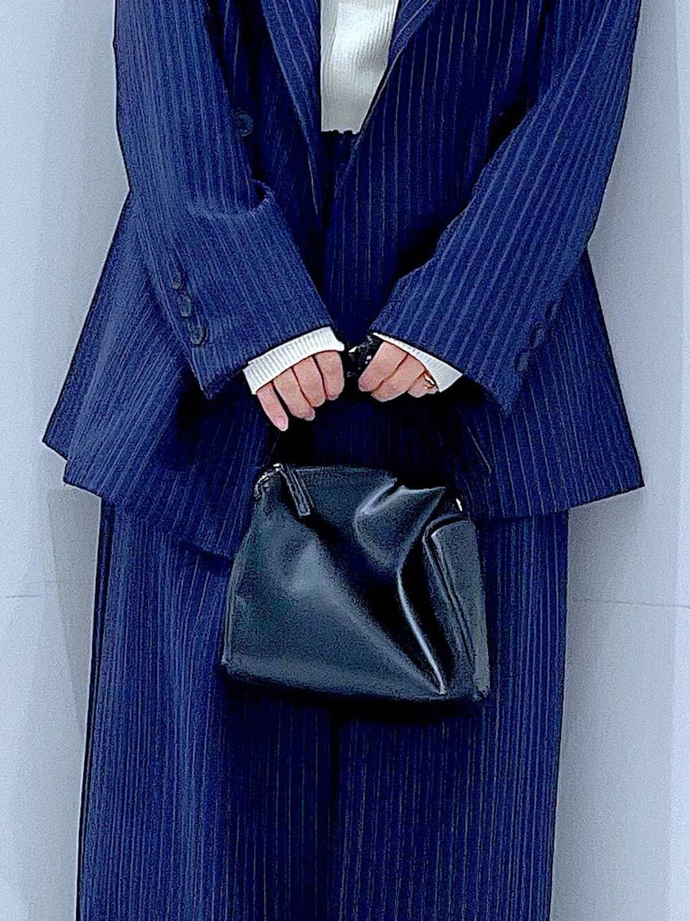 ブラック系のブーツ、ブラック系のショルダーバッグ、ブルー系のスラックスを着用したレディースの冬コーディネートの9枚目の写真