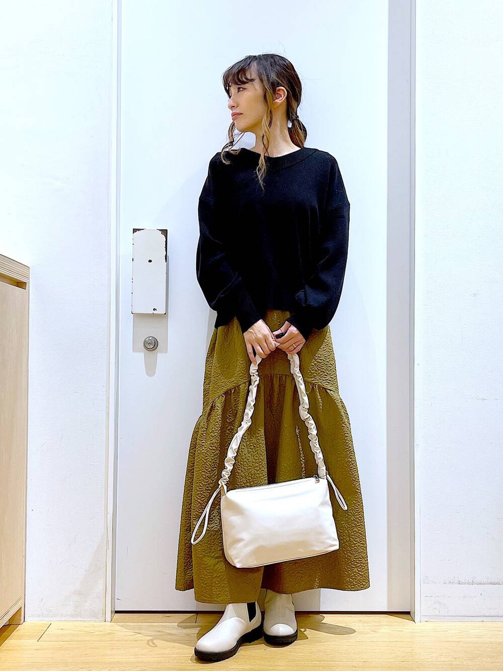 ホワイト系のショルダーバッグ、ベージュ系のブーツ、ブラック系のニット/セーターを着用したレディースの冬コーディネートの3枚目の写真