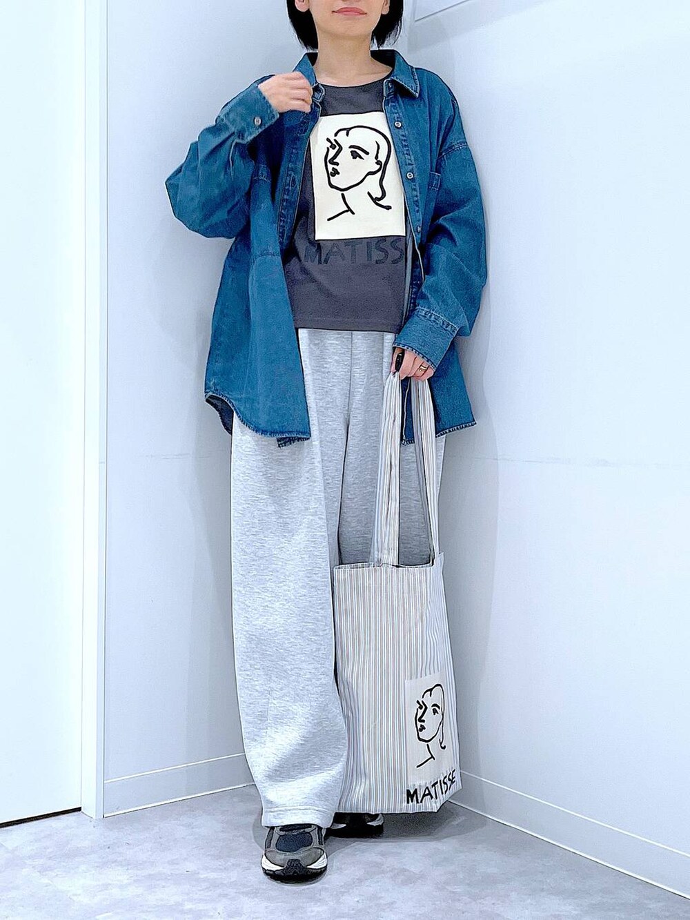 ブルー系のシャツ/ブラウス、ブラウン系のトートバッグ、グレー系のTシャツ/カットソーを着用したレディースの秋コーディネートの6枚目の写真