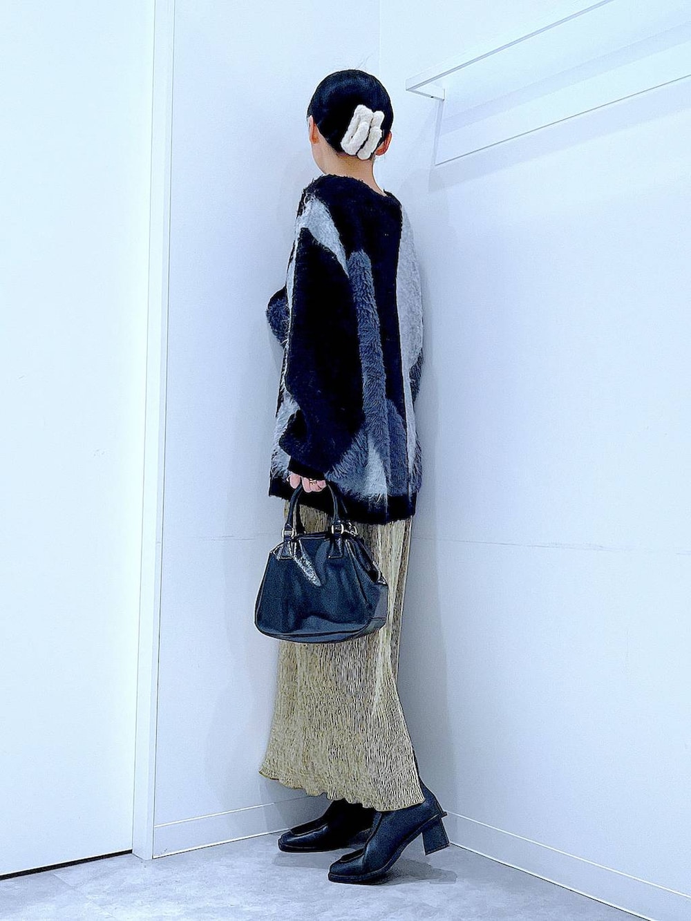 グレー系のニット/セーター、ブラック系のブーツ、ブラック系のショルダーバッグを着用したレディースの冬コーディネートの3枚目の写真