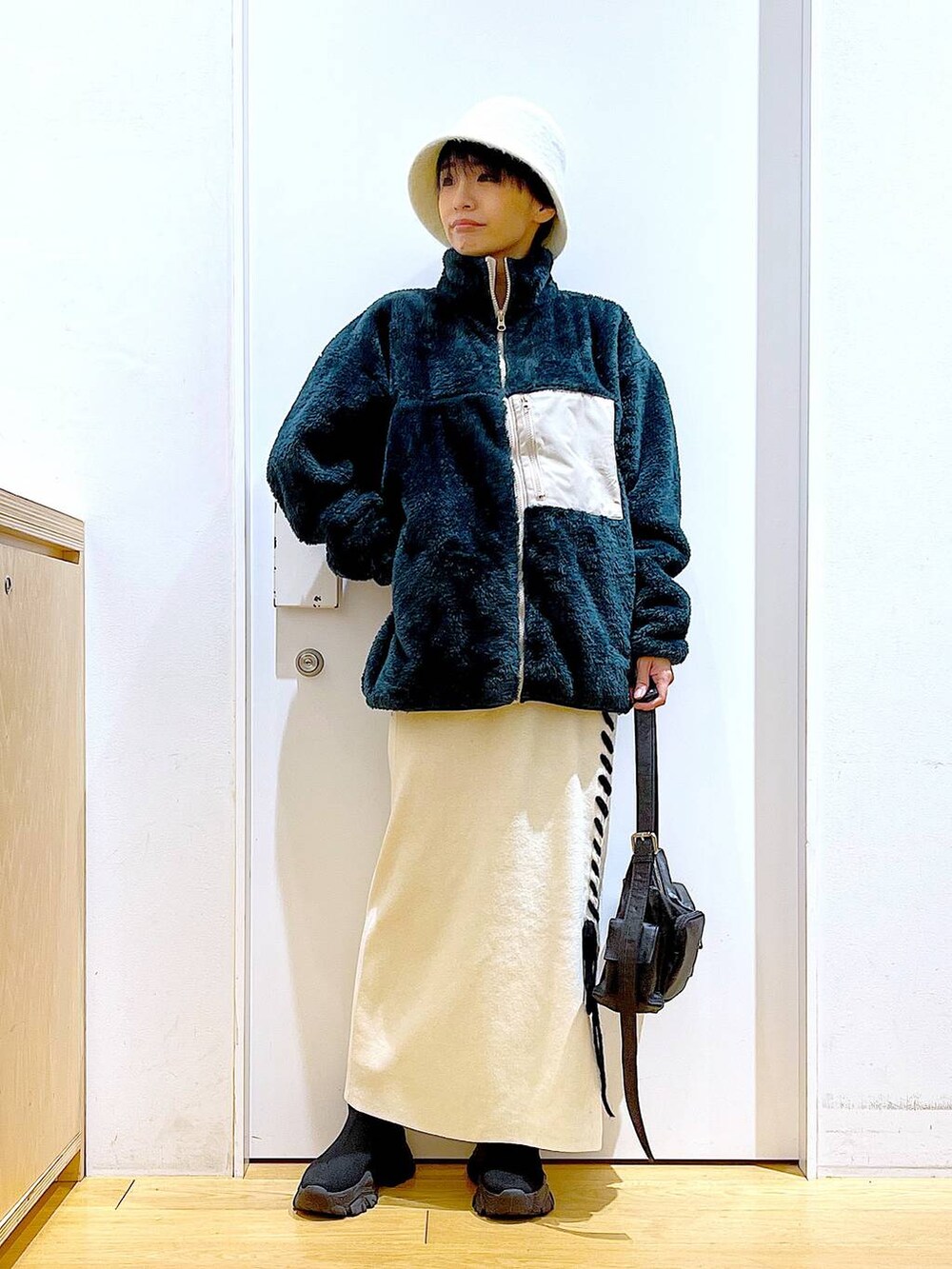 ブラック系のブーツ、ベージュ系のスカート、ブラック系のショルダーバッグを着用したレディースの冬コーディネートの2枚目の写真