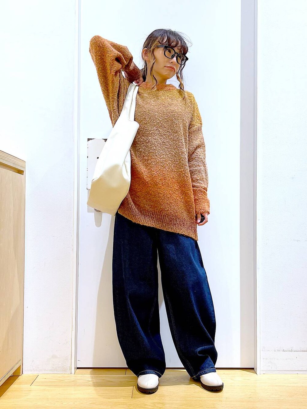 オレンジ系のニット/セーター、ホワイト系のトートバッグ、ベージュ系のブーツを着用したレディースの冬コーディネートの2枚目の写真