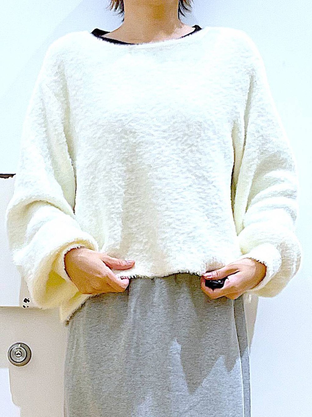 ブラック系のハンドバッグ、ブラック系のブーツ、グレー系のスカートを着用したレディースの冬コーディネートの7枚目の写真