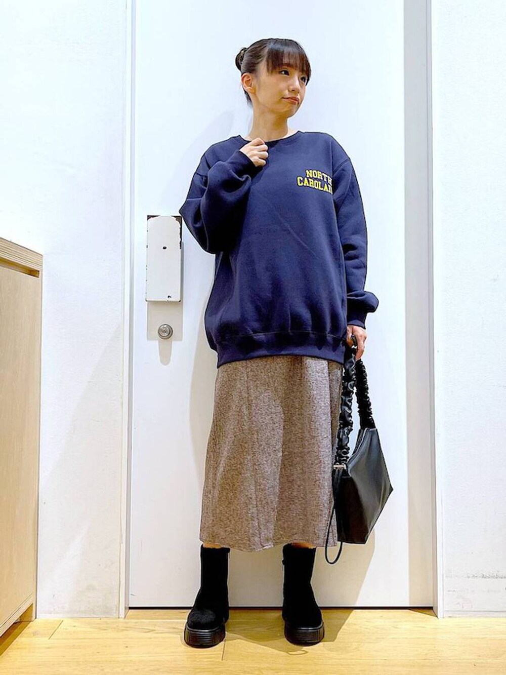 ブラック系のショルダーバッグ、ブラック系のブーツ、ブラウン系のワンピースを着用したレディースの冬コーディネートの2枚目の写真