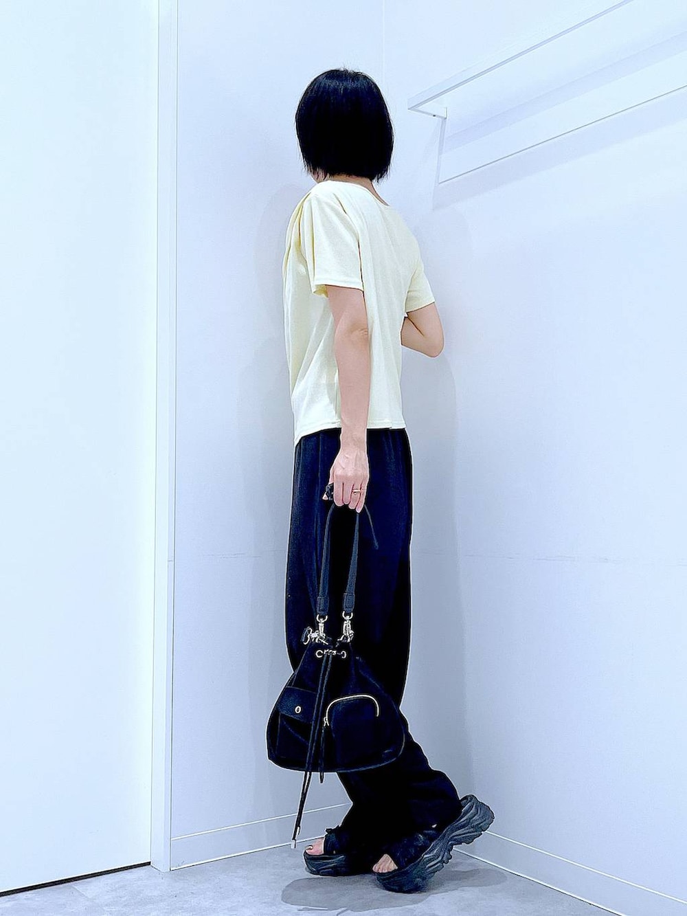 ブラック系のスニーカー、ブラック系のショルダーバッグ、イエロー系のTシャツ/カットソーを着用したレディースの夏コーディネートの3枚目の写真