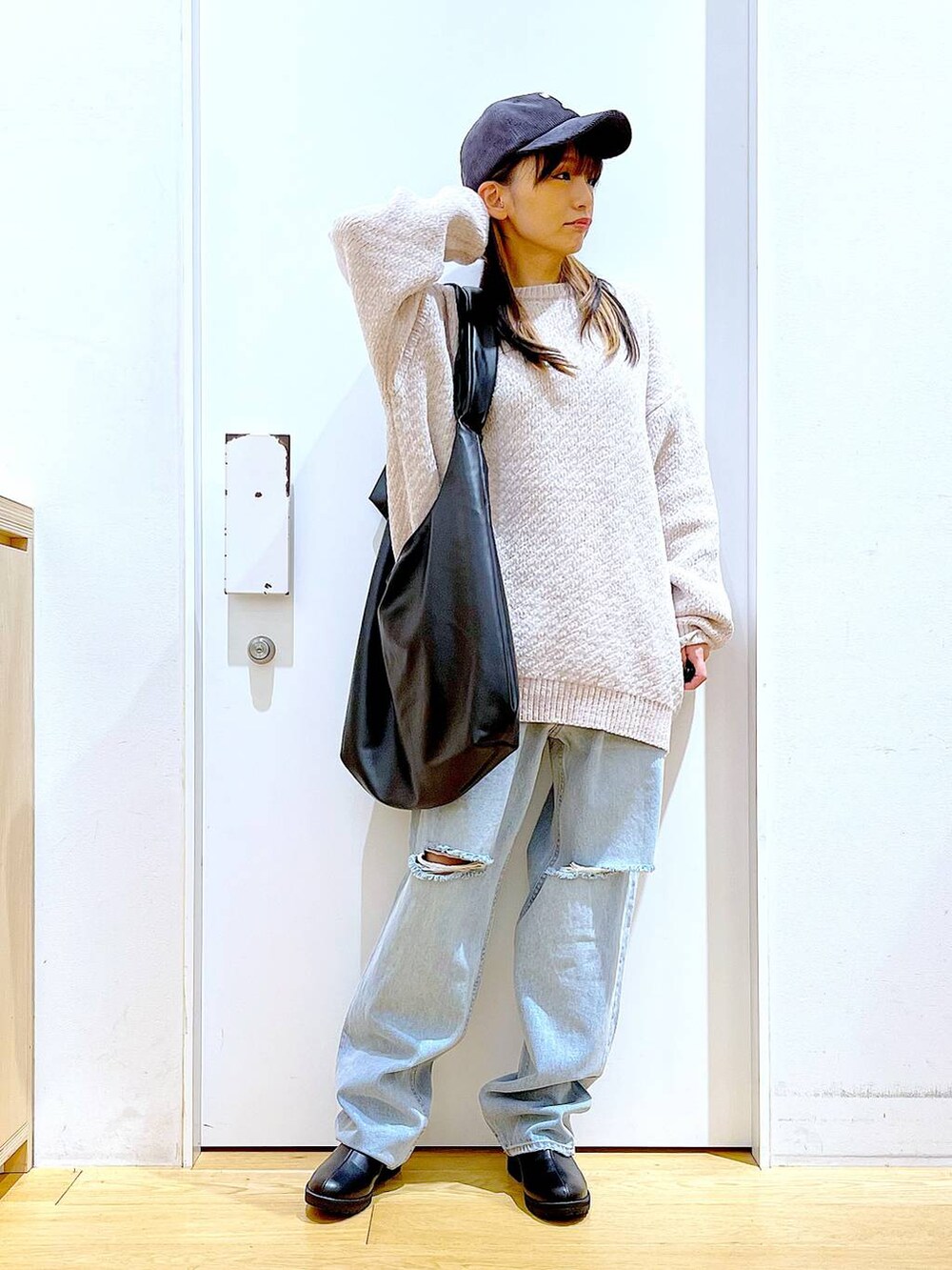 ホワイト系のニット/セーター、ブラック系のショルダーバッグ、ブラック系のブーツを着用したレディースの冬コーディネートの2枚目の写真