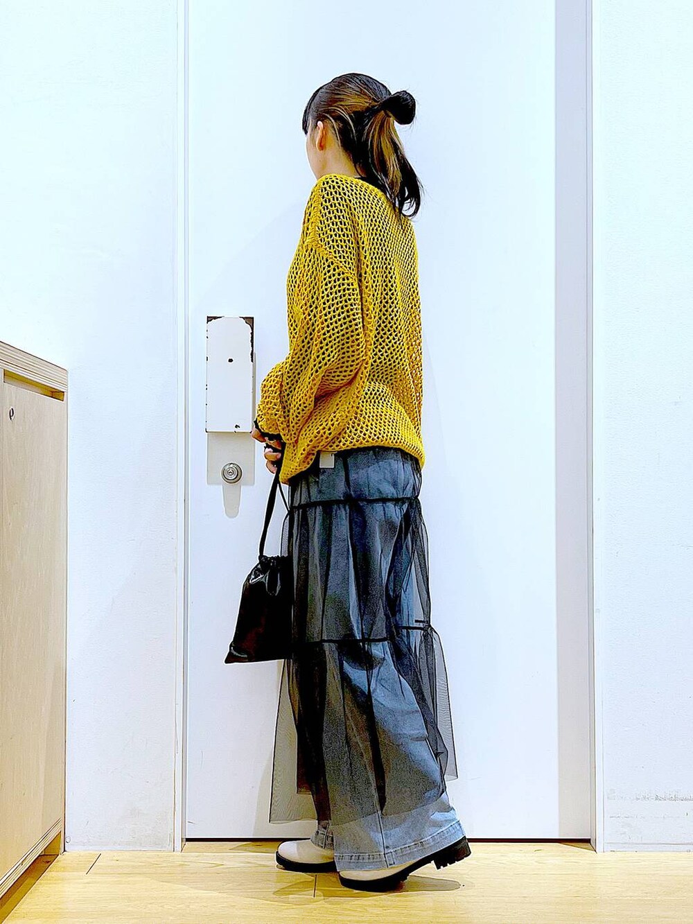 ブルー系のデニムパンツ、ブラック系のTシャツ/カットソー、オレンジ系のニット/セーターを着用したレディースの冬コーディネートの3枚目の写真