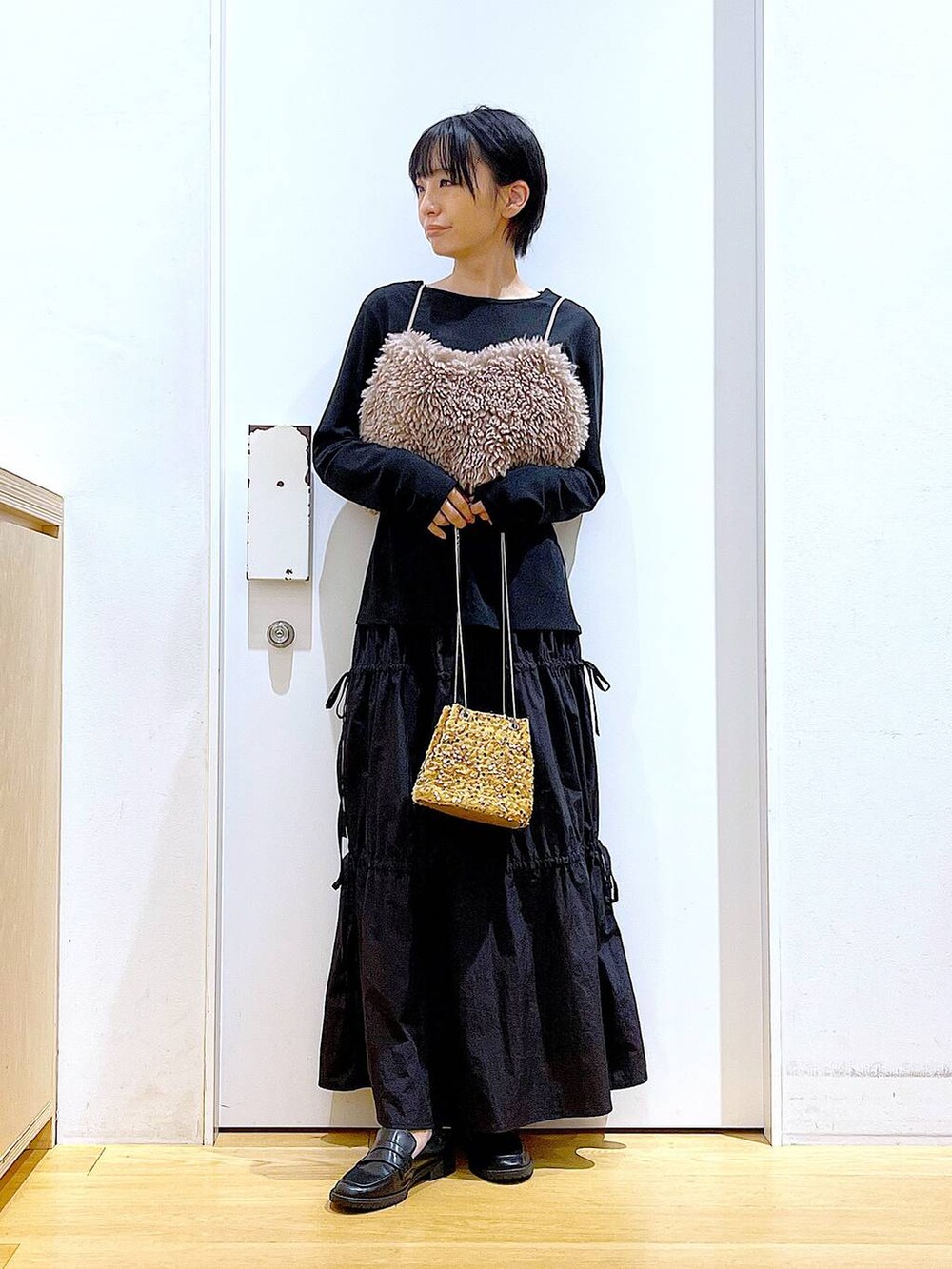 ブラウン系のベスト、ベージュ系のショルダーバッグ、ブラック系のTシャツ/カットソーを着用したレディースの秋コーディネートの2枚目の写真