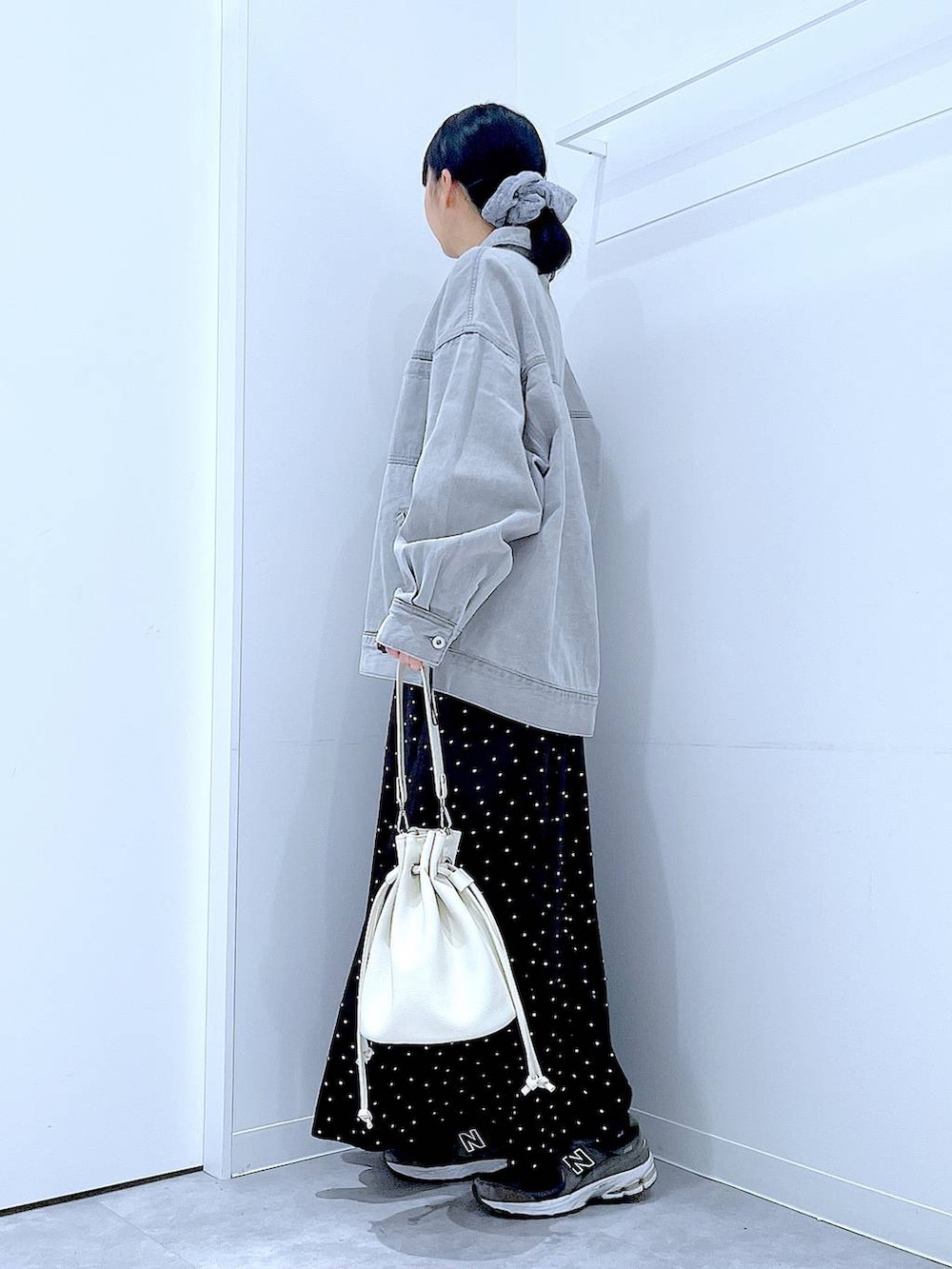 グレー系のデニムジャケット、ホワイト系のショルダーバッグ、グレー系のシュシュを着用したレディースの春コーディネートの3枚目の写真