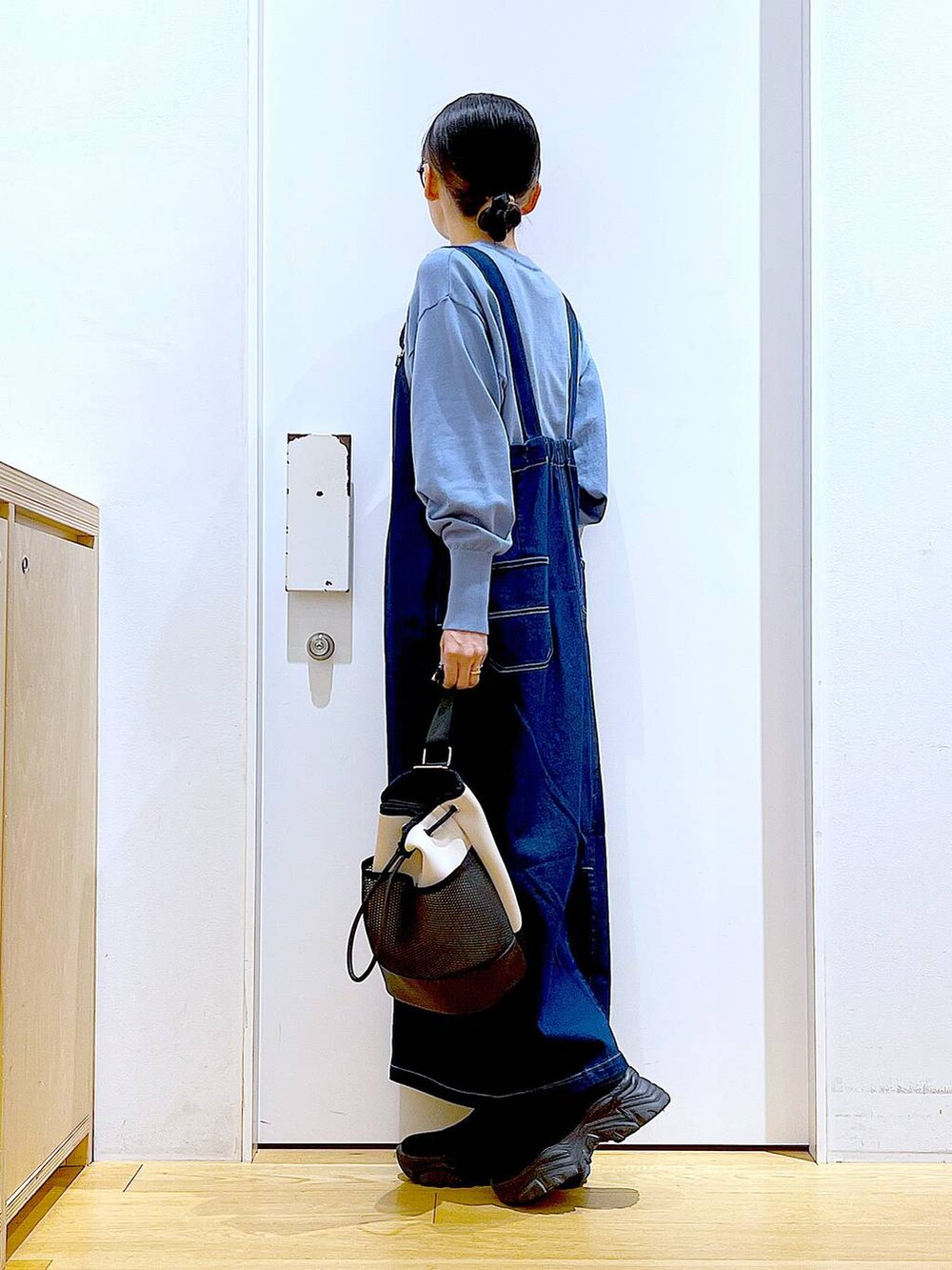 ブルー系のジャンパースカート、ブルー系のカーディガン/ボレロ、ブラック系のブーツを着用したレディースの春コーディネートの3枚目の写真