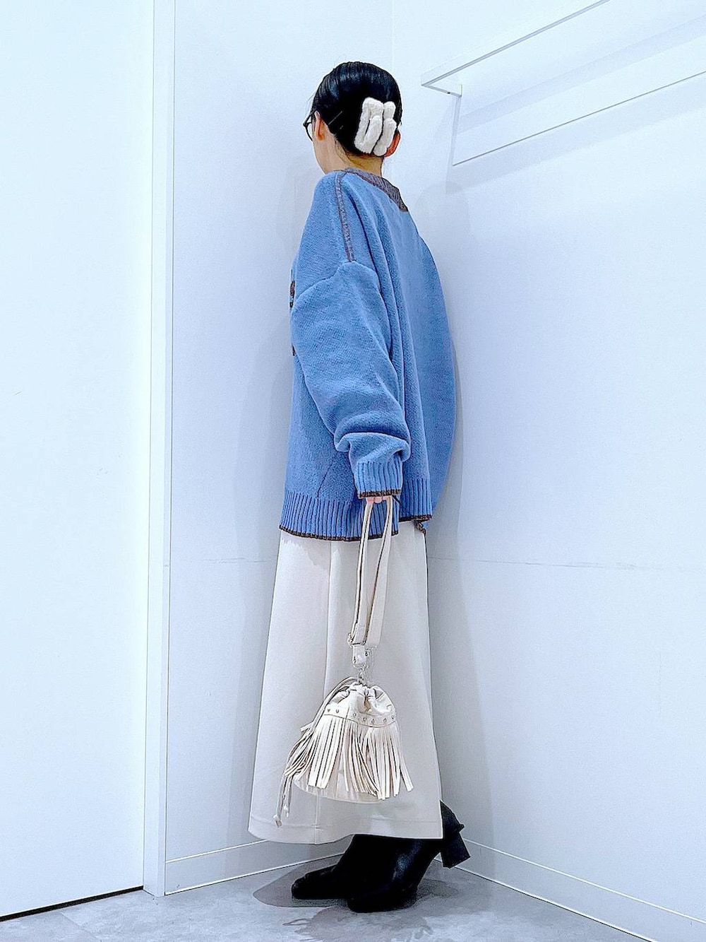 ベージュ系のスカート、ブラック系のブーツ、ホワイト系のショルダーバッグを着用したレディースの冬コーディネートの3枚目の写真