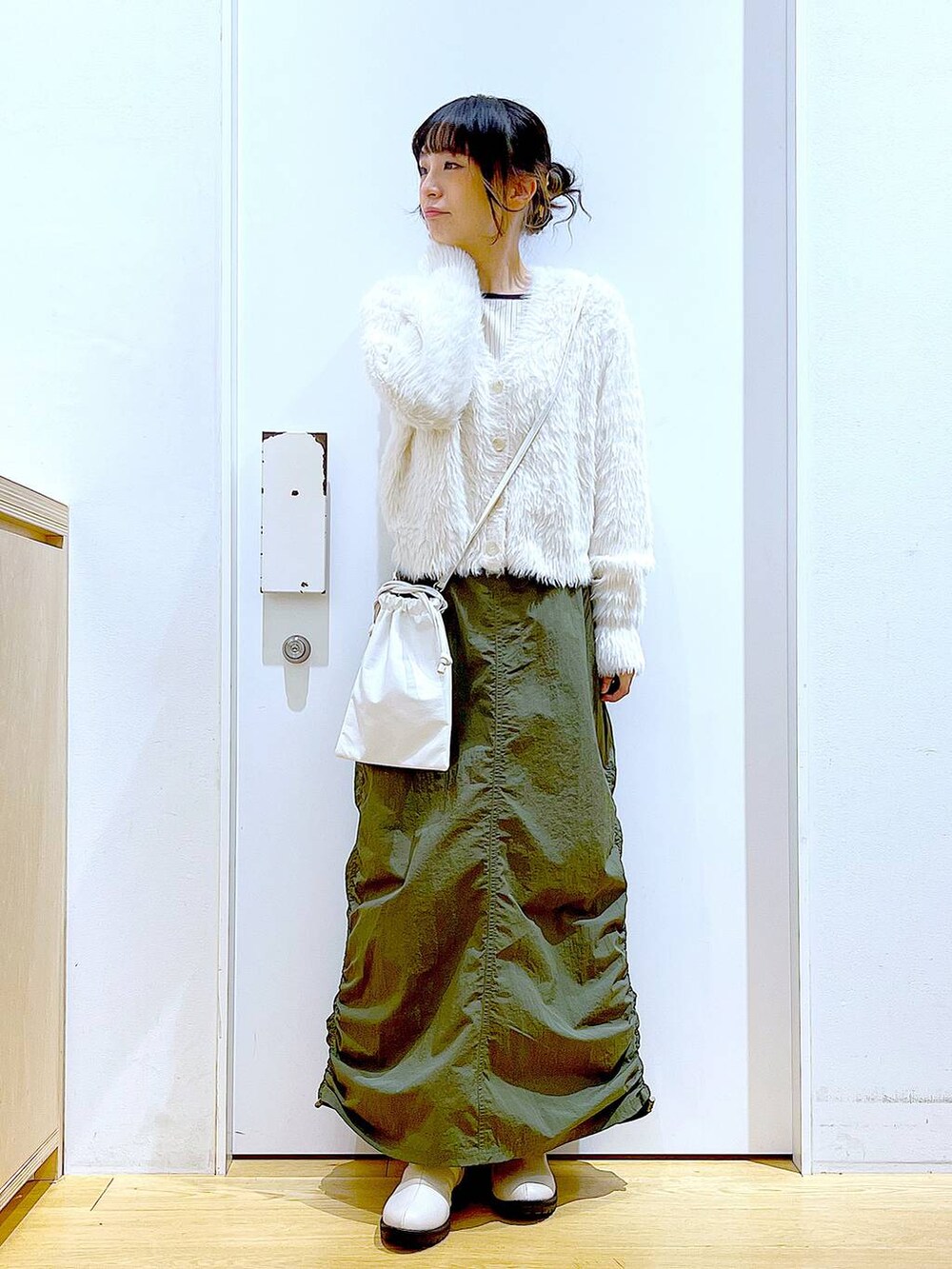 ベージュ系のブーツ、ベージュ系のニット/セーター、グリーン系のスカートを着用したレディースの冬コーディネートの2枚目の写真