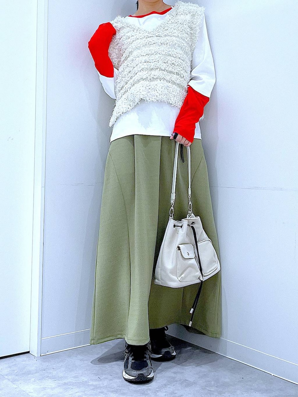 グリーン系のスカート、ホワイト系のTシャツ/カットソー、ベージュ系のベストを着用したレディースの冬コーディネートの6枚目の写真