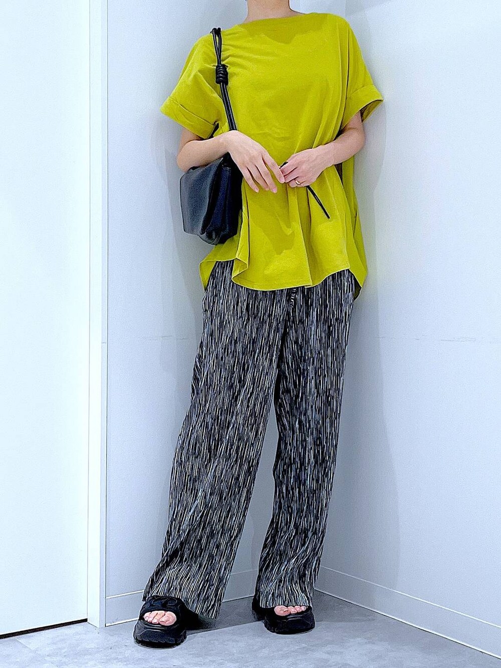 ブラック系のスニーカー、ブラック系のショルダーバッグ、グリーン系のTシャツ/カットソーを着用したレディースの夏コーディネートの6枚目の写真