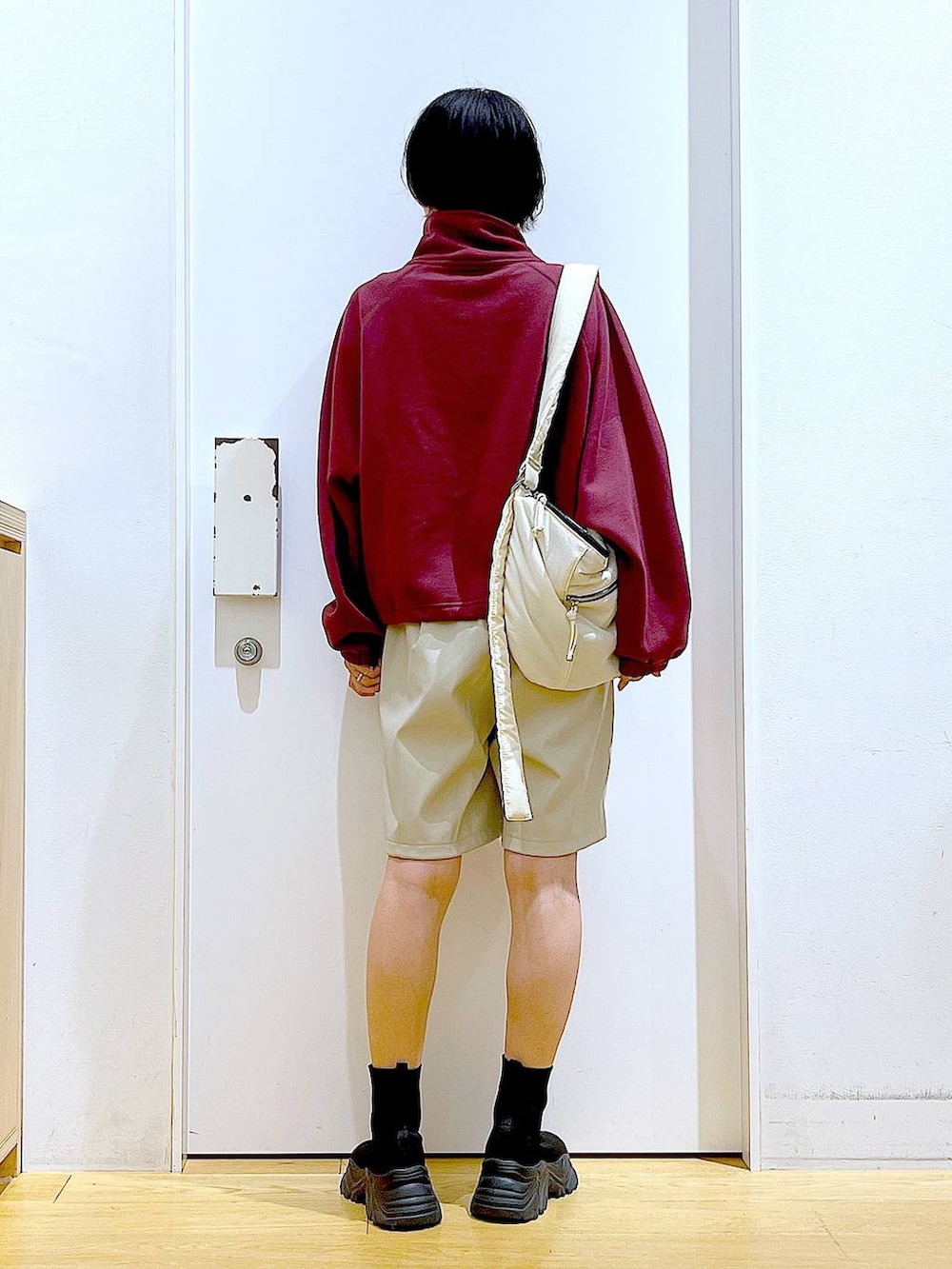 ホワイト系のショルダーバッグ、ブラック系のブーツ、レッド系のスウェットを着用したレディースの冬コーディネートの5枚目の写真