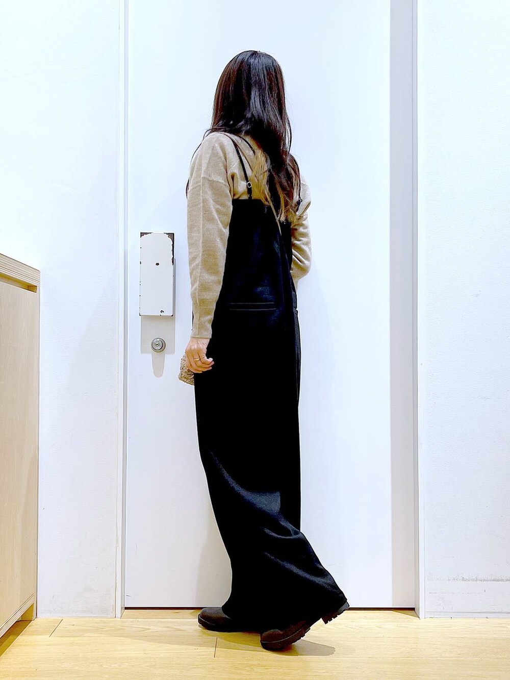 ベージュ系のニット/セーター、ブラック系のブーツ、ブラウン系のクラッチバッグを着用したレディースの冬コーディネートの3枚目の写真