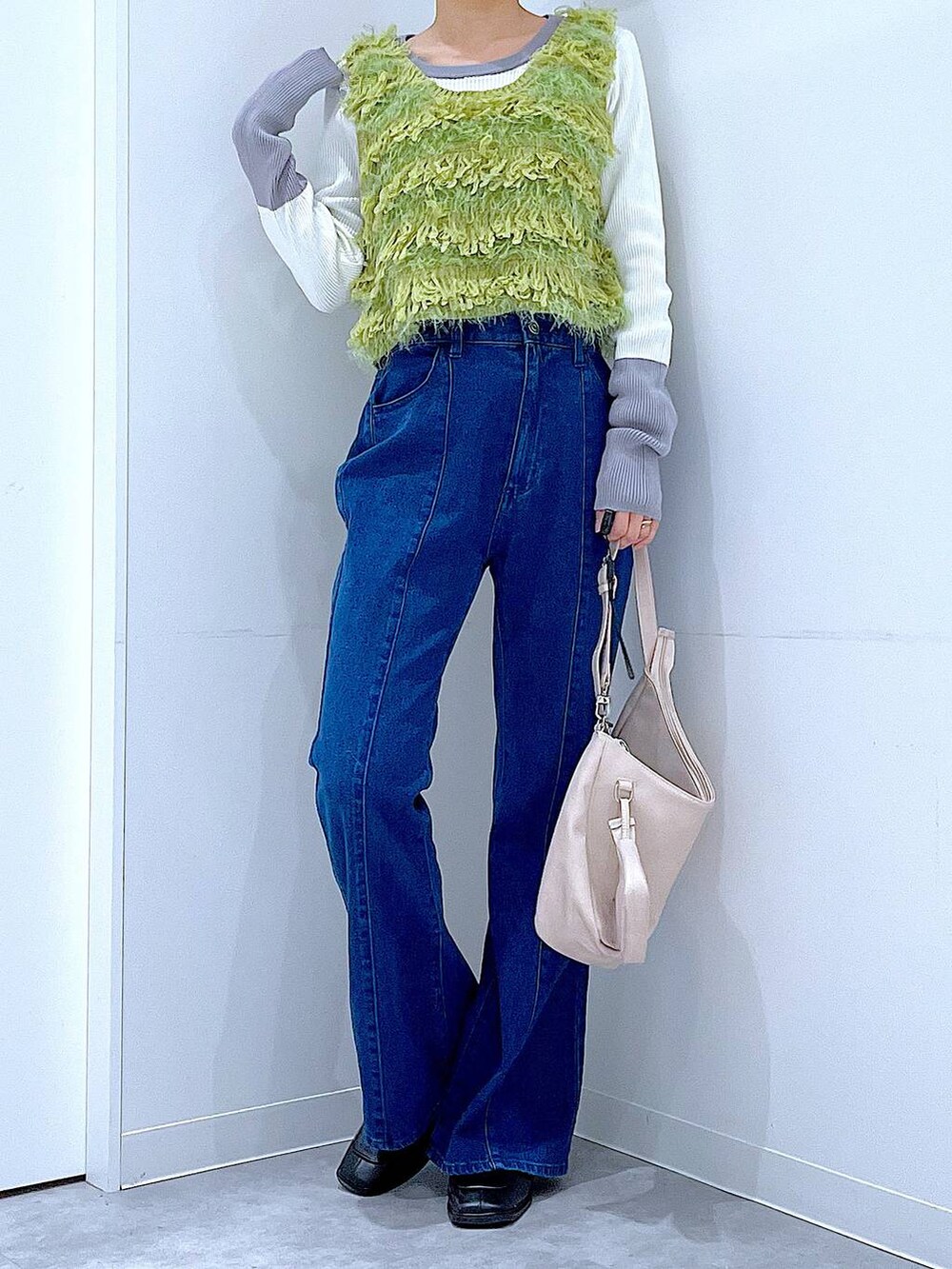 ブラック系のブーツ、ホワイト系のショルダーバッグ、グリーン系のベストを着用したレディースの春コーディネートの6枚目の写真