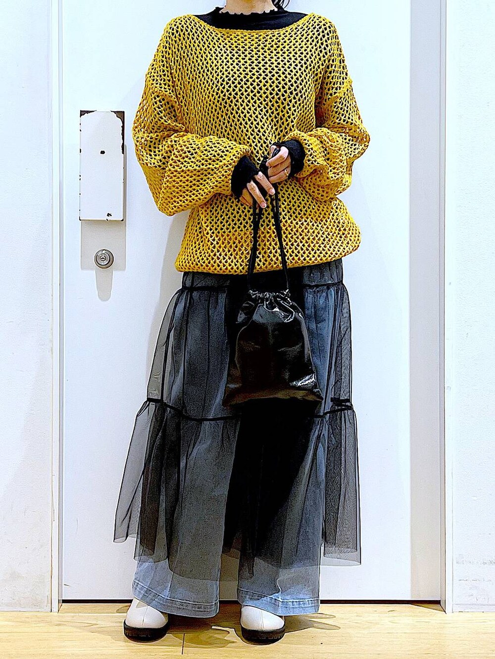 ブルー系のデニムパンツ、ブラック系のTシャツ/カットソー、オレンジ系のニット/セーターを着用したレディースの冬コーディネートの6枚目の写真