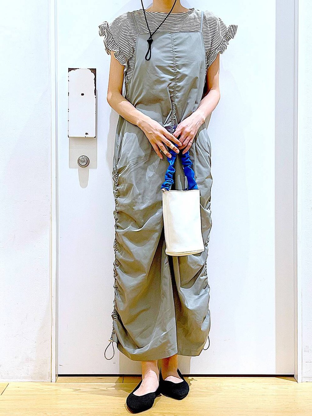 ブルー系のショルダーバッグ、ブラック系のパンプス、グリーン系のワンピースを着用したレディースの春コーディネートの6枚目の写真