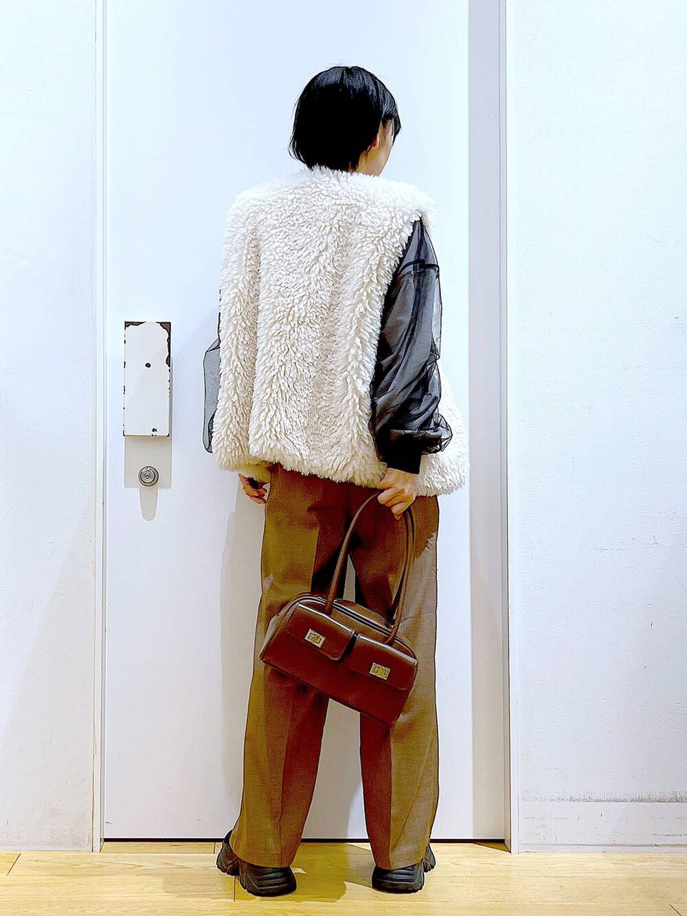 ベージュ系のベスト、ブラウン系のハンドバッグ、ブラック系のブーツを着用したレディースの冬コーディネートの5枚目の写真