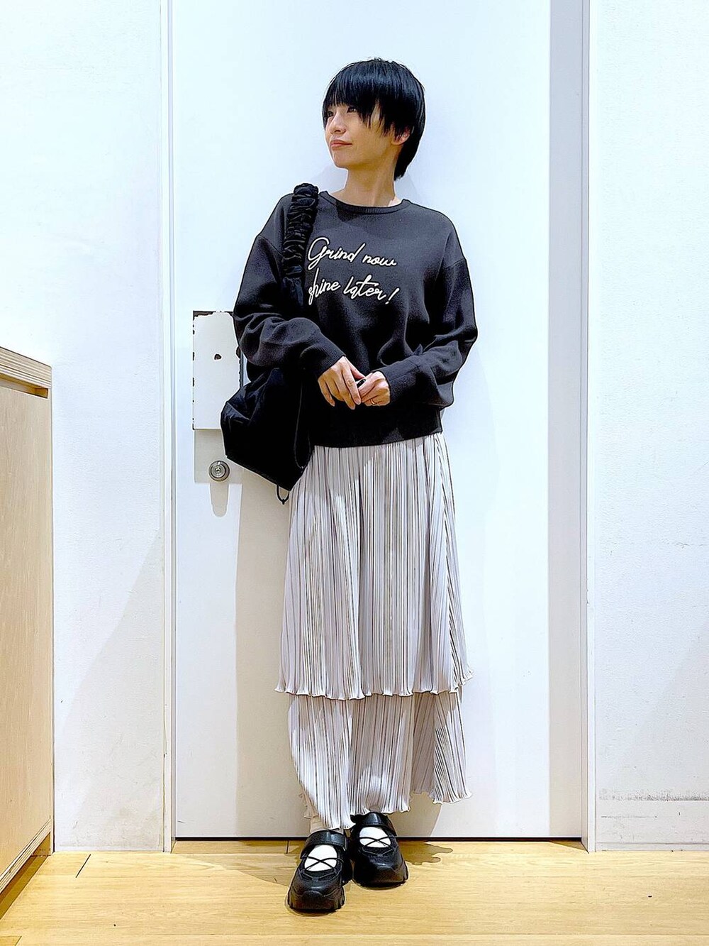 ブラック系のショルダーバッグ、ブラック系のスニーカー、グレー系のニット/セーターを着用したレディースの夏コーディネートの2枚目の写真