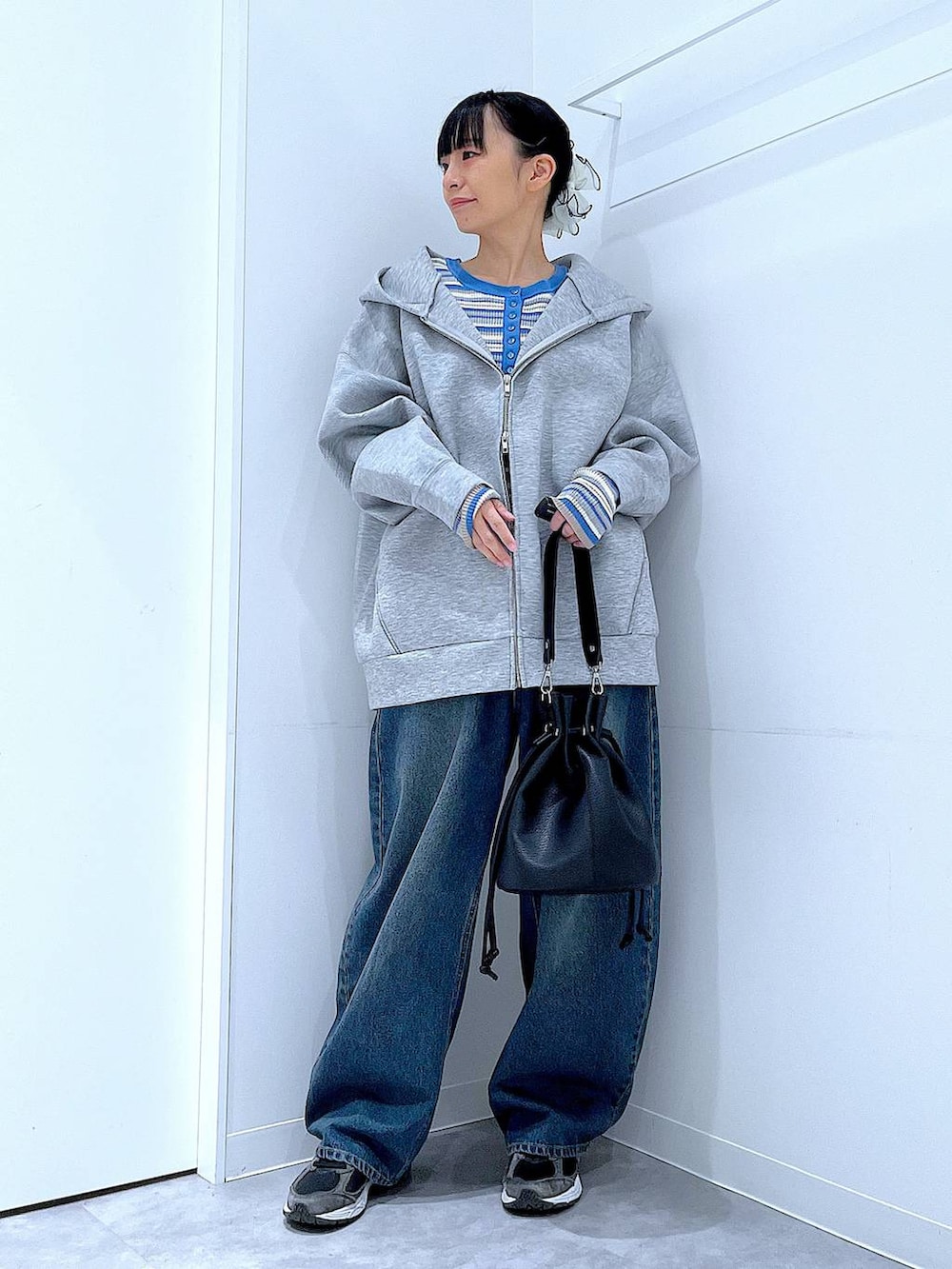 ブルー系のデニムパンツ、グレー系のパーカー、ブラック系のショルダーバッグを着用したレディースの冬コーディネートの2枚目の写真