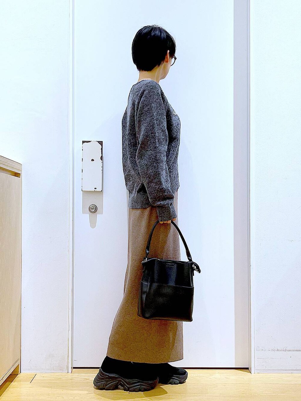 ブラック系のブーツ、ブラック系のショルダーバッグ、ブラウン系のスカートを着用したレディースの冬コーディネートの4枚目の写真