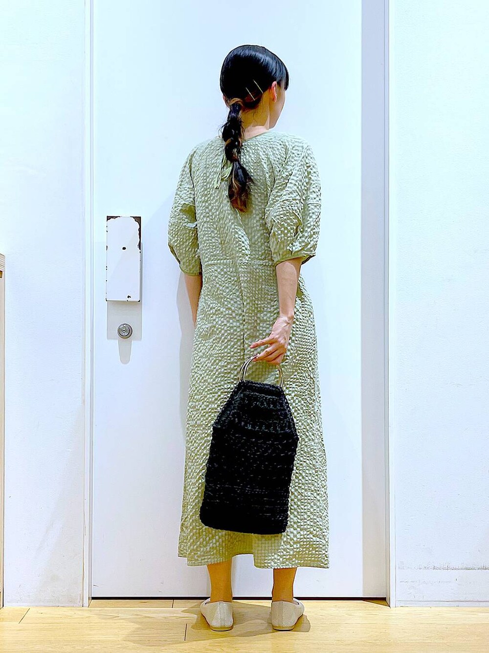 グリーン系のワンピース、ホワイト系のパンプス、ブラック系のハンドバッグを着用したレディースの春コーディネートの5枚目の写真