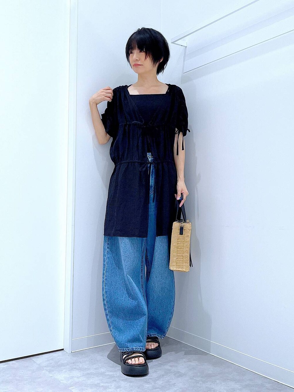 ブルー系のデニムパンツ、ベージュ系のショルダーバッグ、ブラック系のサンダルを着用したレディースの夏コーディネートの2枚目の写真