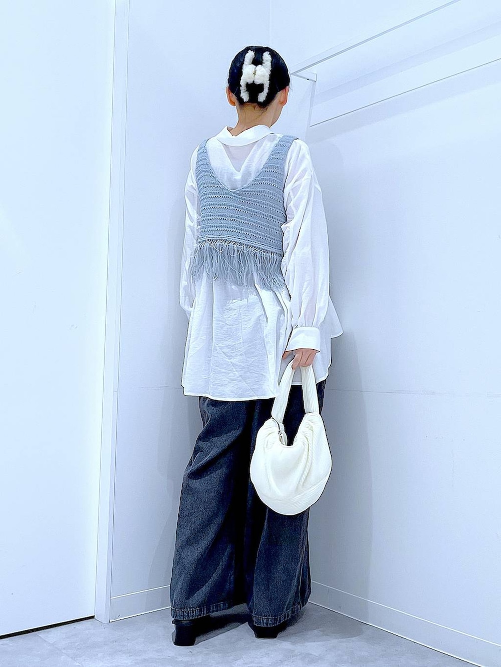 ブラック系のブーツ、ブルー系のベスト、ホワイト系のショルダーバッグを着用したレディースの春コーディネートの5枚目の写真