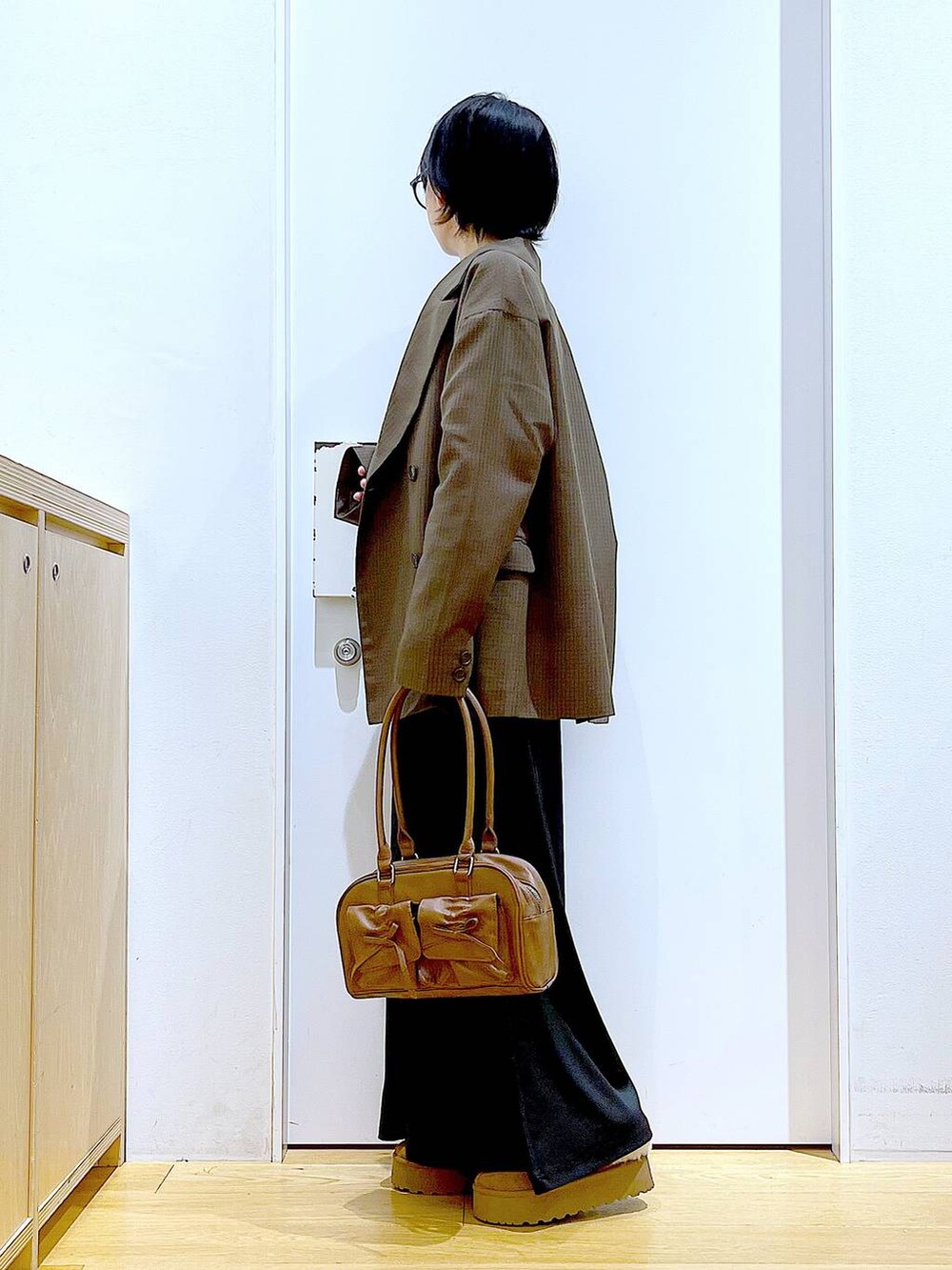 ベージュ系のスリッポン、ブラウン系のハンドバッグ、ブラウン系のテーラードジャケットを着用したレディースの秋コーディネートの3枚目の写真