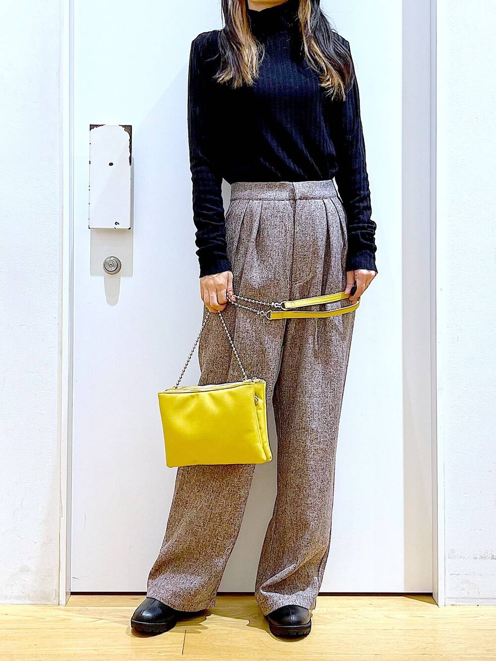 イエロー系のショルダーバッグ、ブラック系のブーツ、ブラウン系のその他パンツを着用したレディースの冬コーディネートの6枚目の写真