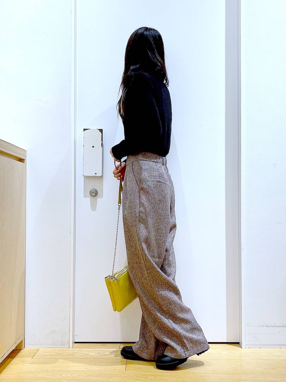 イエロー系のショルダーバッグ、ブラック系のブーツ、ブラウン系のその他パンツを着用したレディースの冬コーディネートの3枚目の写真