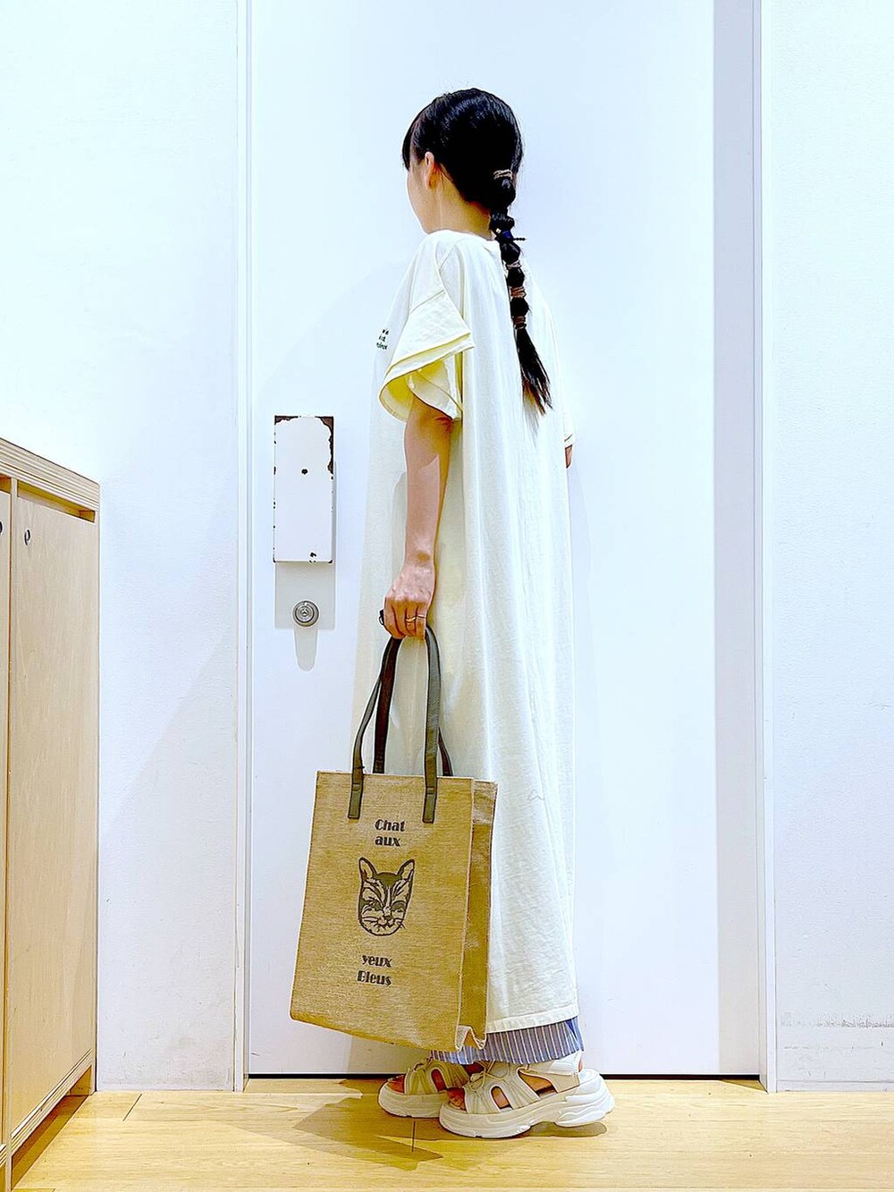 ホワイト系のサンダル、ベージュ系のワンピース、グレー系のトートバッグを着用したレディースの夏コーディネートの3枚目の写真