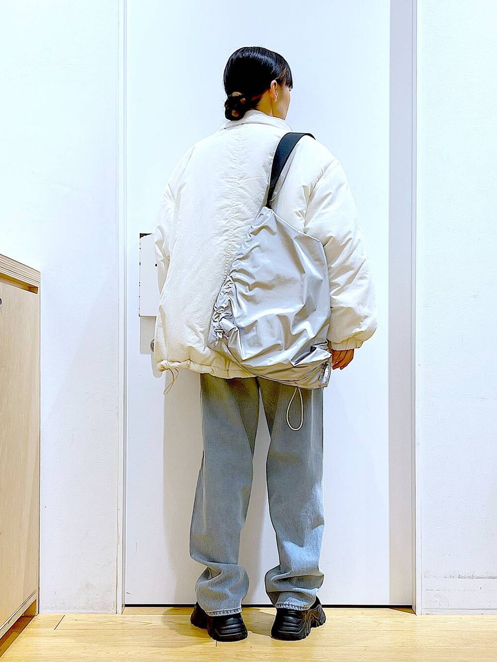 ブラック系のブーツ、ブルー系のデニムパンツ、シルバー系のショルダーバッグを着用したレディースの冬コーディネートの5枚目の写真