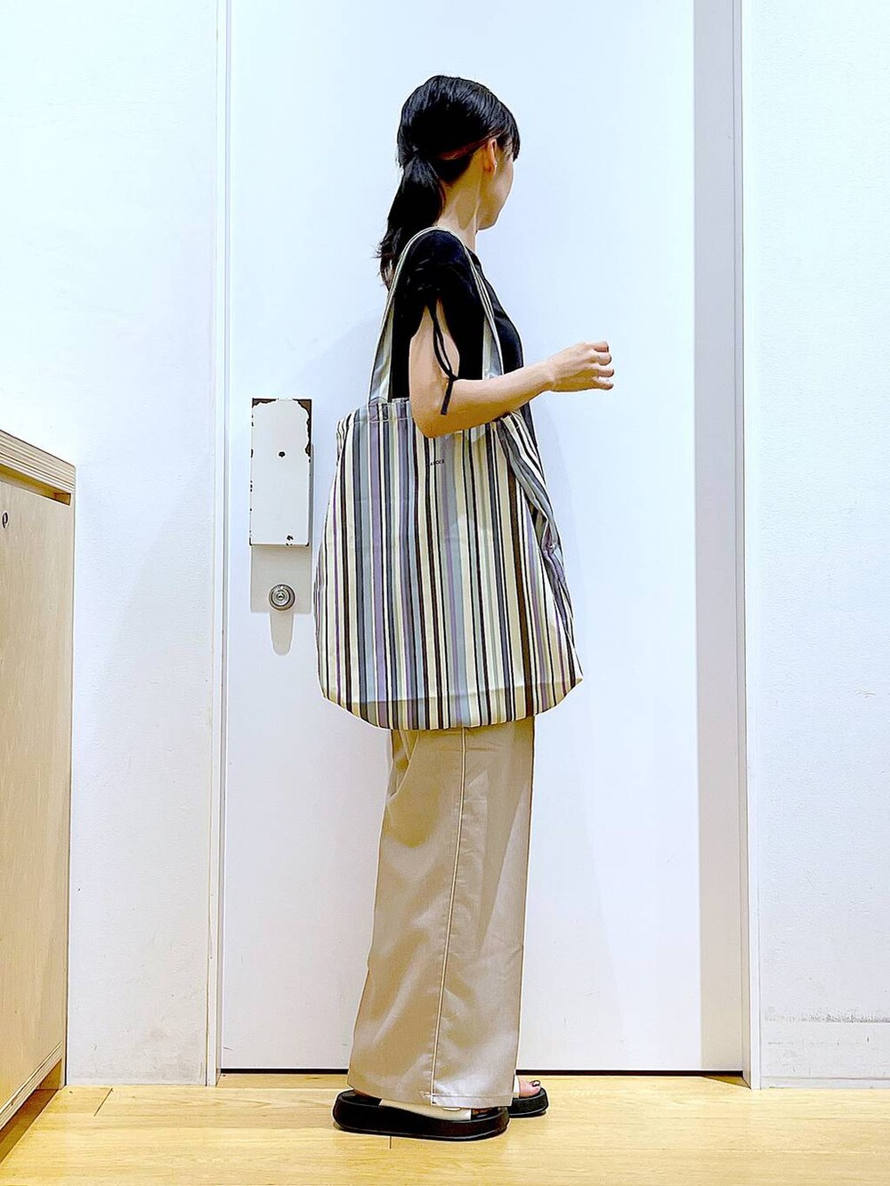 ホワイト系のサンダル、グリーン系のトートバッグ、ベージュ系のスラックスを着用したレディースの秋コーディネートの4枚目の写真