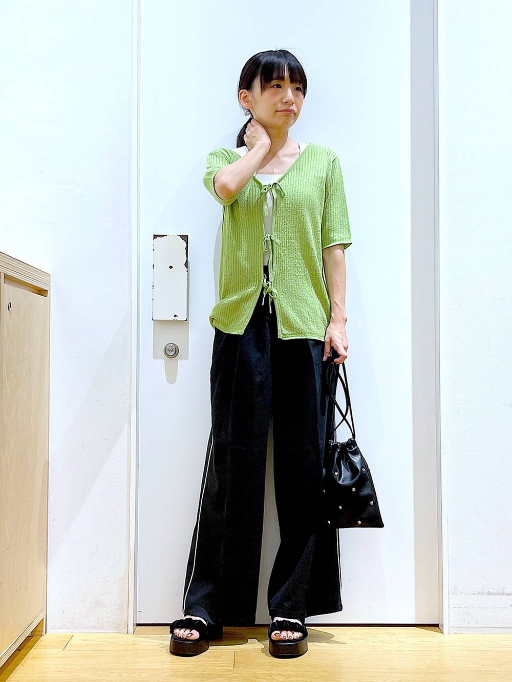 ブラック系のサンダル、ホワイト系のニット/セーター、ブラック系のショルダーバッグを着用したレディースの夏コーディネートの2枚目の写真