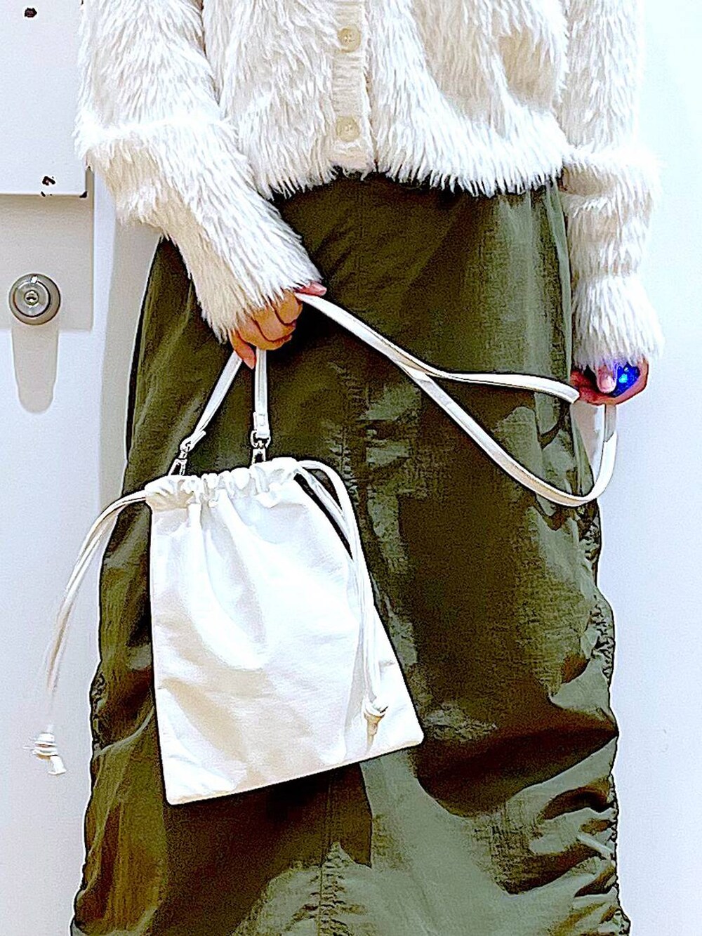 ベージュ系のブーツ、ベージュ系のニット/セーター、グリーン系のスカートを着用したレディースの冬コーディネートの9枚目の写真