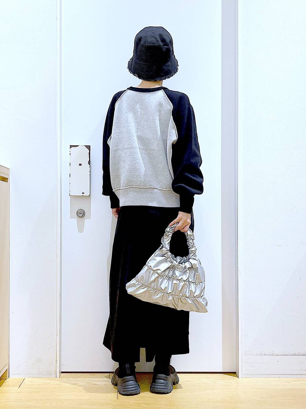 ブラック系のブーツ、シルバー系のショルダーバッグ、ブラック系のニット/セーターを着用したレディースの冬コーディネートの5枚目の写真