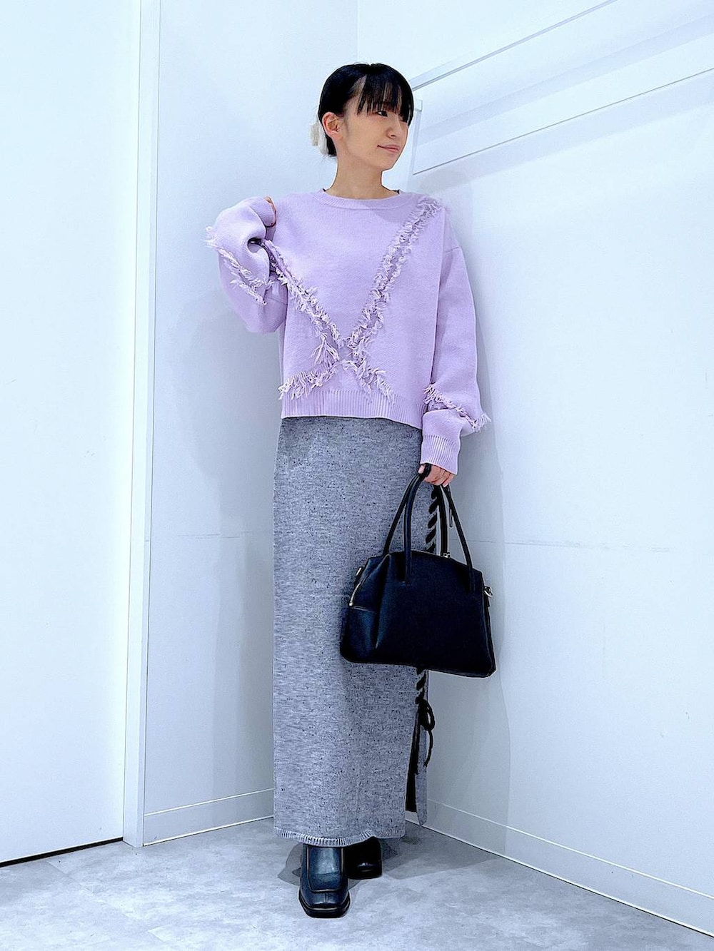 ブラック系のボストンバッグ、グレー系のスカート、ブラック系のブーツを着用したレディースの冬コーディネートの2枚目の写真
