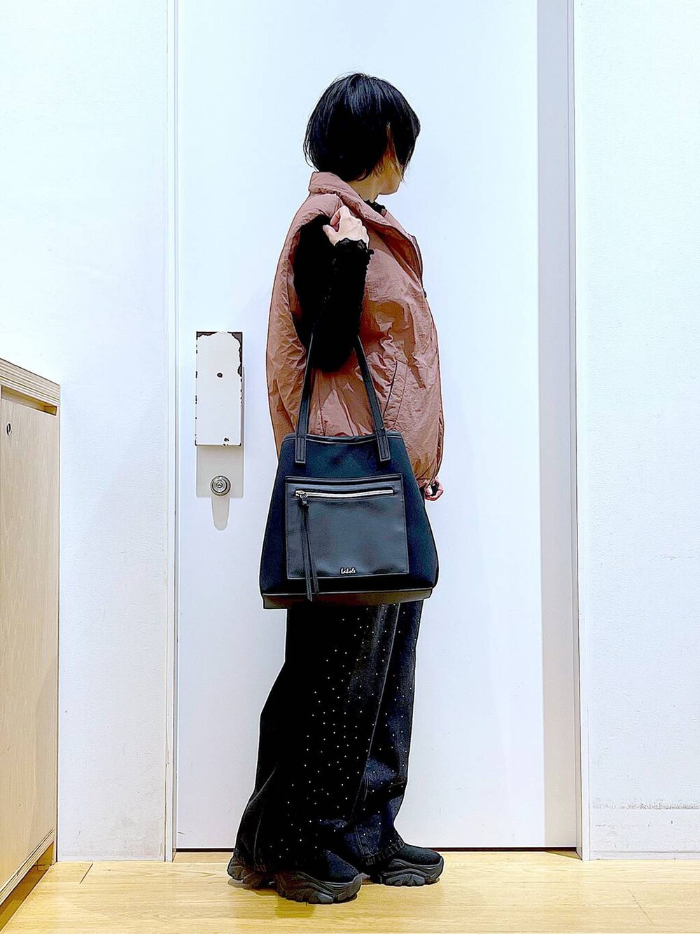 ブラウン系のベスト、ブラック系のトートバッグ、ブラック系のTシャツ/カットソーを着用したレディースの秋コーディネートの4枚目の写真