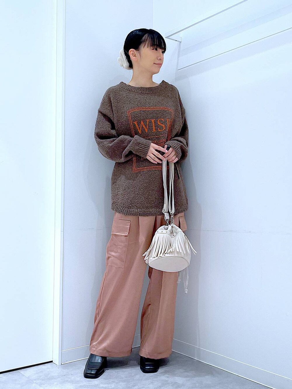 ブラウン系のニット/セーター、ブラック系のブーツ、ホワイト系のショルダーバッグを着用したレディースの冬コーディネートの2枚目の写真