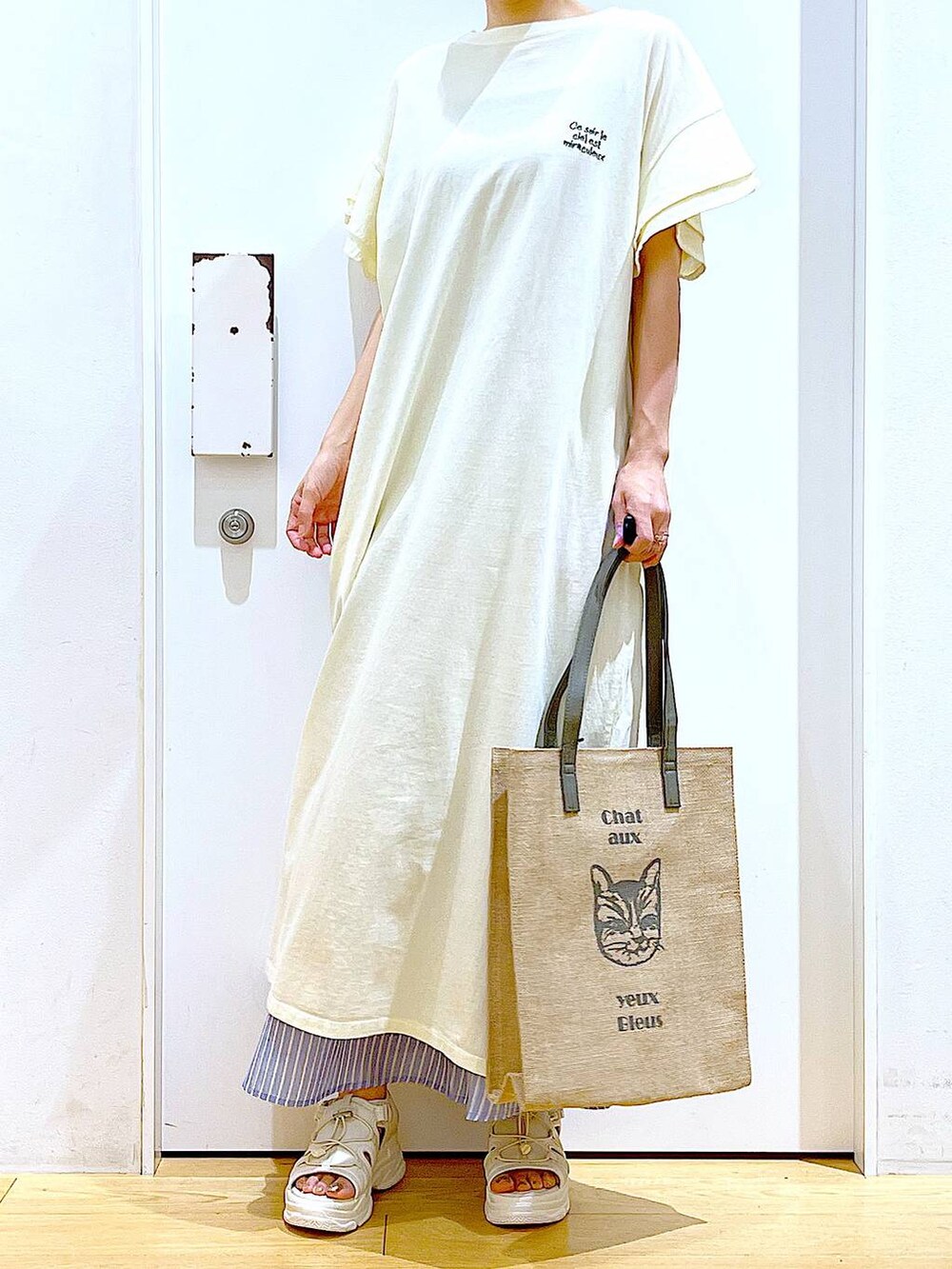 ホワイト系のサンダル、ベージュ系のワンピース、グレー系のトートバッグを着用したレディースの夏コーディネートの6枚目の写真