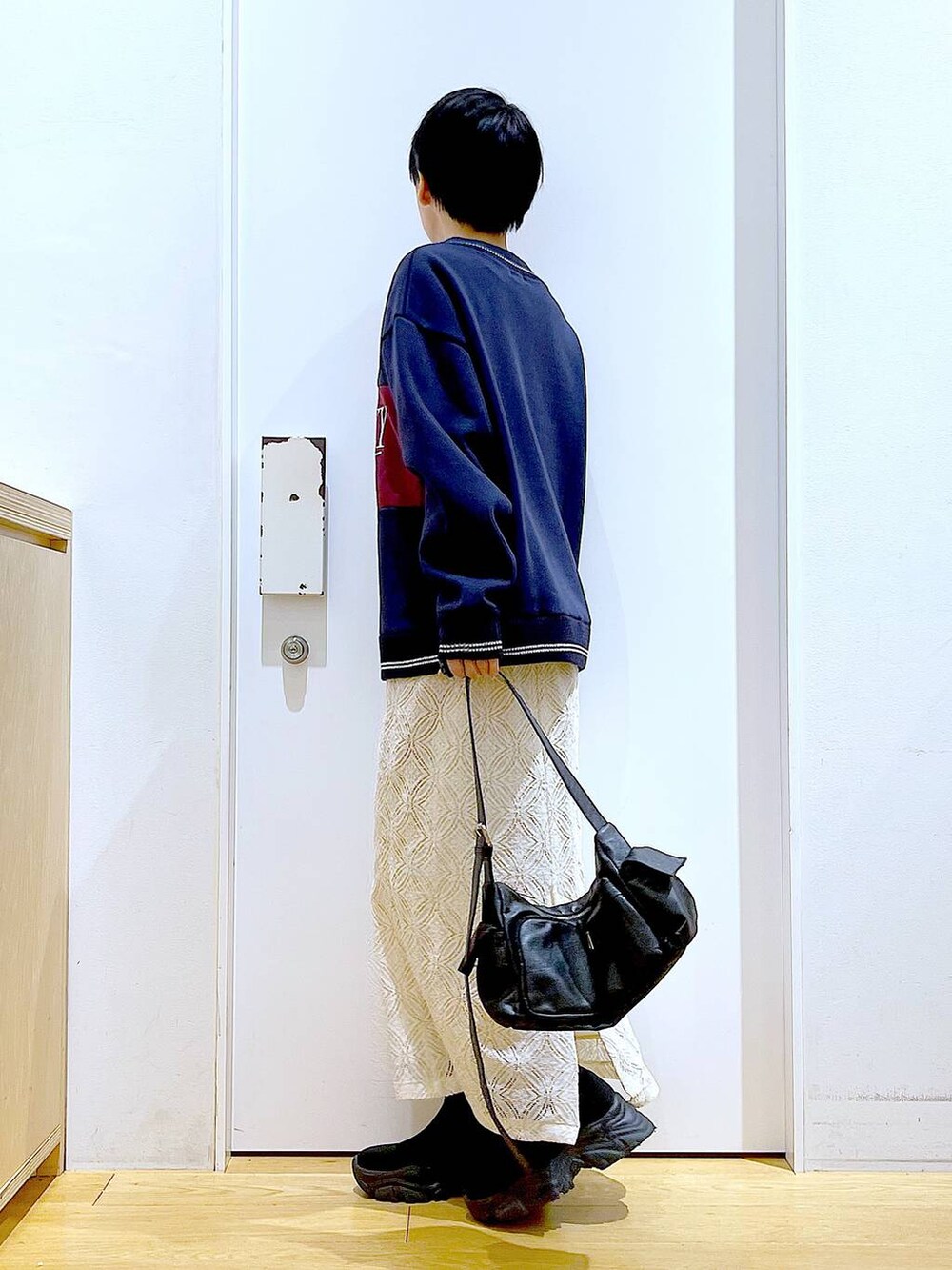 ブラック系のブーツ、ホワイト系のスカート、ブラック系のショルダーバッグを着用したレディースの冬コーディネートの3枚目の写真