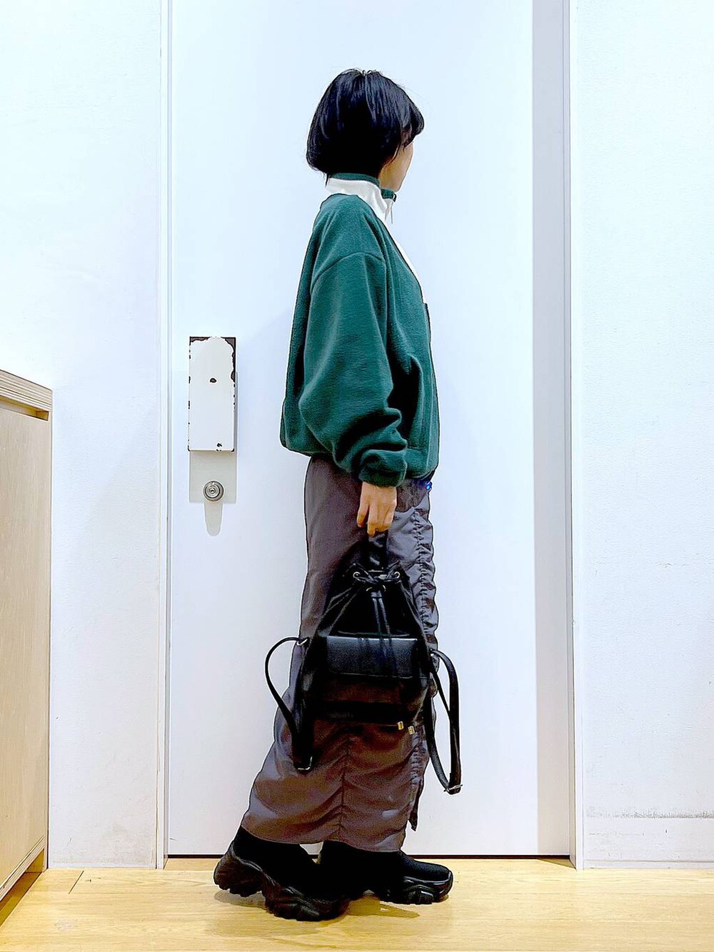 ブラック系のバックパック/リュック、グレー系のスカート、ブラック系のブーツを着用したレディースの冬コーディネートの4枚目の写真