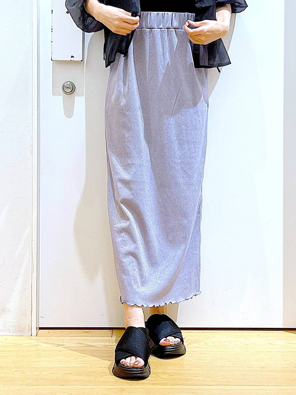 パープル系のスカート、ブラック系のサンダル、ブラック系のニット/セーターを着用したレディースの夏コーディネートの8枚目の写真