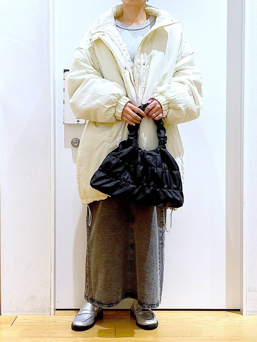 シルバー系のローファー、ホワイト系のその他アウター、ブラック系のショルダーバッグを着用したレディースの冬コーディネートの6枚目の写真