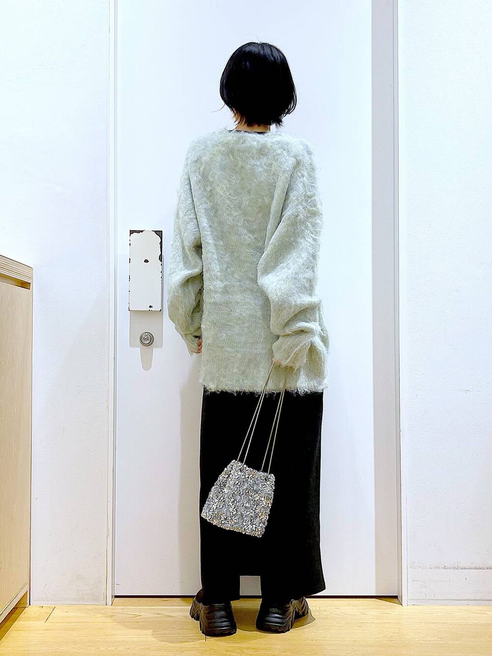 グリーン系のカーディガン/ボレロ、ブラック系のブーツ、ブラック系のスカートを着用したレディースの冬コーディネートの5枚目の写真