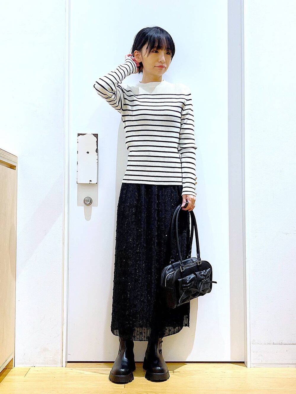 ホワイト系のニット/セーター、ブラック系のハンドバッグ、ブラック系のブーツを着用したレディースの秋コーディネートの2枚目の写真