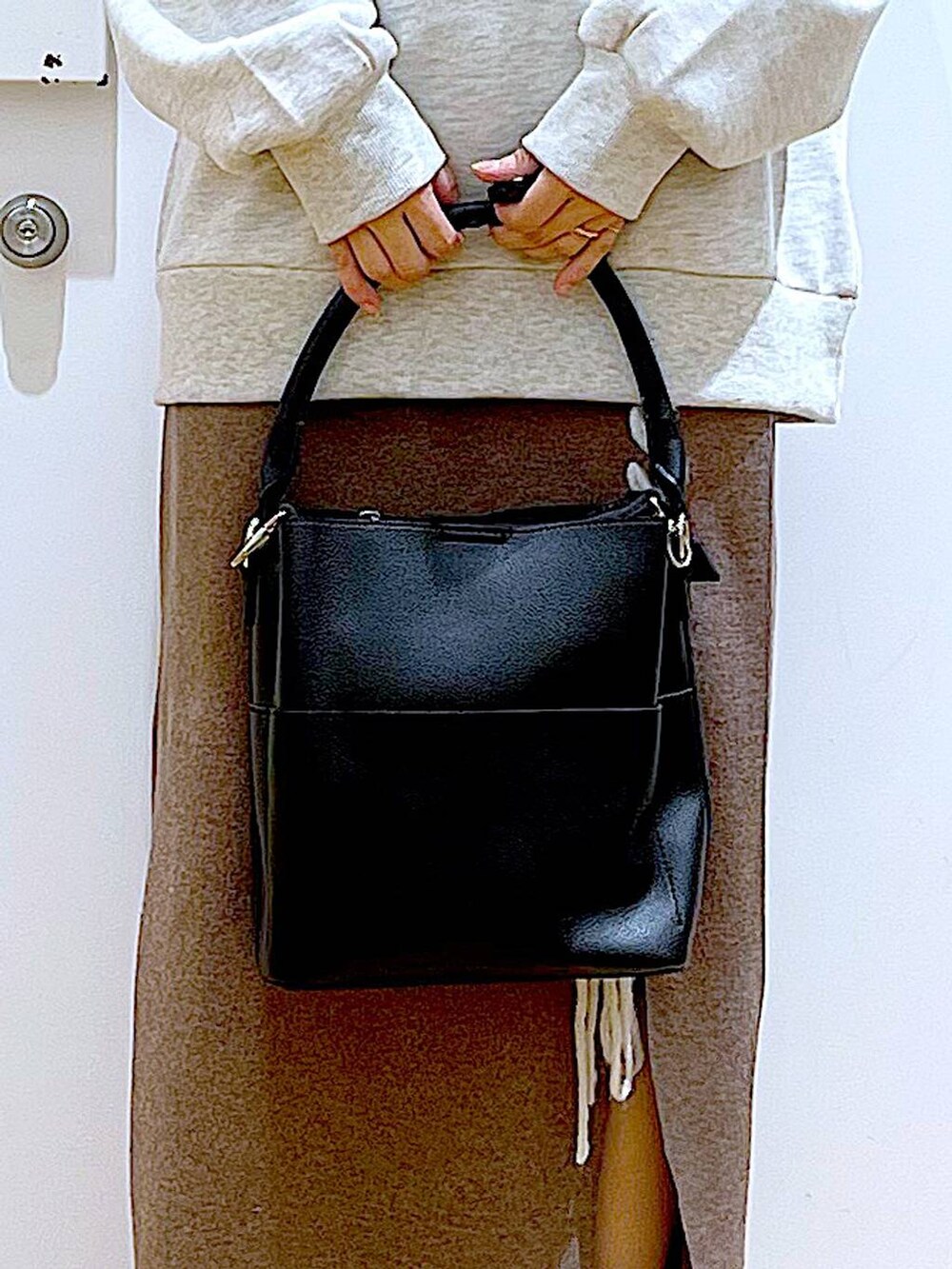 ブラック系のショルダーバッグ、ブラック系のブーツ、ブラウン系のスカートを着用したレディースの冬コーディネートの9枚目の写真